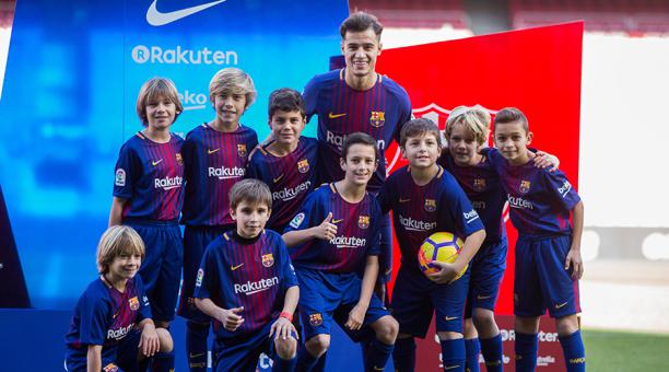 El centrocampista brasileño, Philippe Coutinho, el fichaje más caro de la historia del Barcelona, posa con un grupo de alumnos de la escuela de fúbol del FC Barcelna en el césped del Camp Nou durante su presentación como nuevo jugador azulgrana