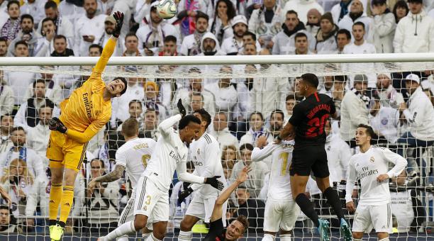 El guardameta belga Thibaut Courtois (i) del Real Madrid, intenta despejar el balón ante el Sevilla. FOTO: EFE