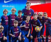 El centrocampista brasileño, Philippe Coutinho, el fichaje más caro de la historia del Barcelona, posa con un grupo de alumnos de la escuela de fúbol del FC Barcelna en el césped del Camp Nou durante su presentación como nuevo jugador azulgrana