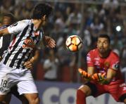 El golero Ever Caballero (18) contiene el balón ante el cabezazo del paraguayo Cristian Riveros. Foto: AFP